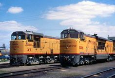 two yellow trains sitting on the tracks next to each other