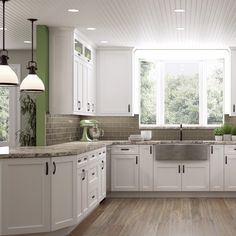 a large kitchen with white cabinets and wood flooring, along with green walls in the background