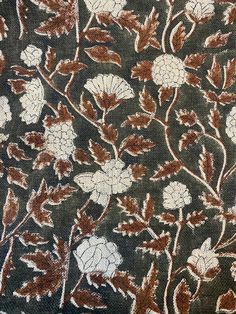 an embroidered cloth with flowers and leaves on it's side, in brown and white colors