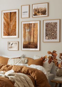 a bed sitting in a bedroom next to a window covered in blankets and pillows with pictures on the wall above it