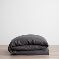 two dark gray sheets folded on top of each other in front of a white wall