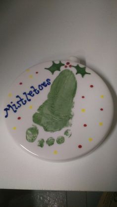 a white plate with a green handprinted christmas ornament on the side