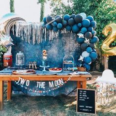 a woman sitting at a table with balloons and decorations