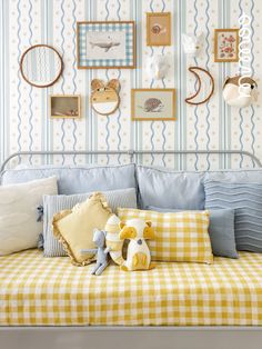 a bed with pillows and stuffed animals on the headboard in front of a striped wall