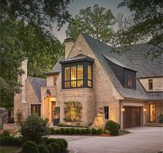 a large brick house with lots of windows and lights on it's front door