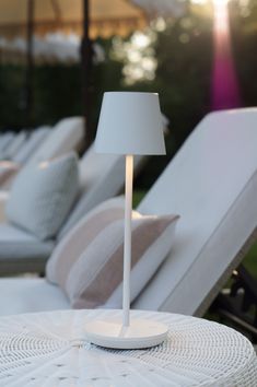 a white lamp sitting on top of a table next to lounge chairs and umbrellas