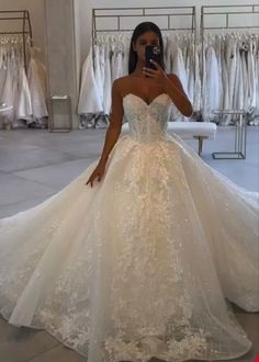 a woman in a wedding dress taking a selfie with her cell phone while looking at the camera