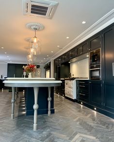 a large kitchen with marble floors and black cabinetry is pictured in this image, there are lights hanging from the ceiling