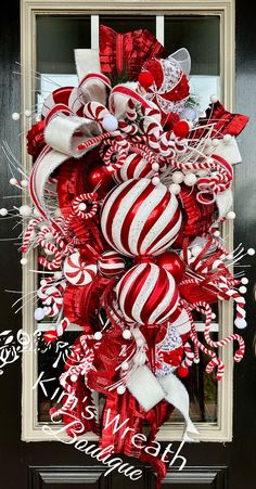 a red and white christmas ornament wreath with candy canes on the front door