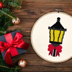 a cross stitch christmas ornament with a red bow on it next to some ornaments