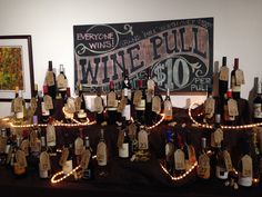 many bottles of wine are lined up on a table with string lights and tags attached to them