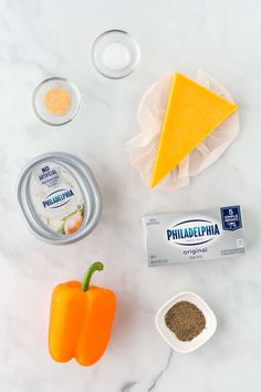 ingredients to make cheese pizza laid out on a white marble counter top, including peppers and seasonings