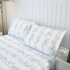 a bed with white sheets and green flowers on it