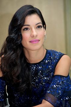 a woman sitting at a table with her hand on her shoulder and looking off to the side