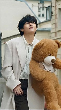 a woman standing next to a brown teddy bear