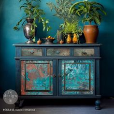 two potted plants sit on top of an old dresser in front of a blue wall