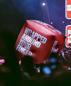 a large red object with the words wrapped around it in front of an audience at a concert