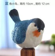 a small blue and white bird sitting on top of a wooden post with chinese writing