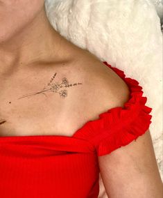 a woman wearing a red dress with a small flower tattoo on her chest and shoulder