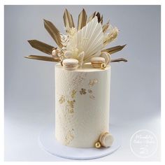 a white and gold decorated cake on a plate with some decorations around the top layer