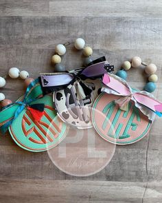 three personalized flip flops with monogrammed bows and beads on a wood floor