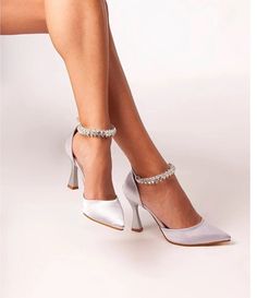 a woman wearing white high heels with silver straps