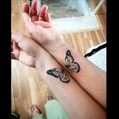 two people holding hands with butterfly tattoos on their wrist and the other one has a small tattoo