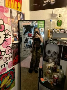 a woman taking a selfie in front of a mirror with skulls on the wall