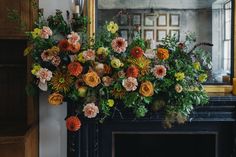 an arrangement of flowers in front of a fireplace