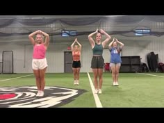 four women are doing exercises on the grass in an indoor gym area with their hands behind their head