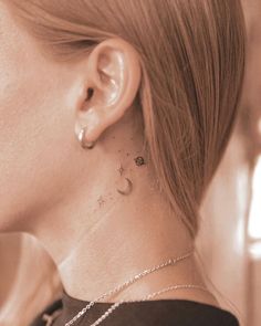 a woman with a small star and moon tattoo on her left side behind the ear