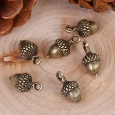 five bronze acorns sitting on top of a wooden table next to pine cones