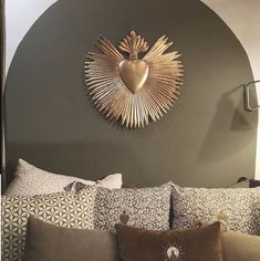 a bed topped with lots of pillows next to a wall mounted sunburst above it