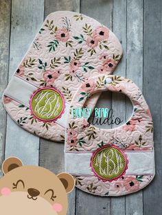 a baby bib with an embroidered monogrammed teddy bear on the front and bottom