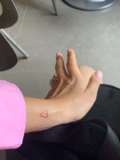 a woman's arm with a small heart tattoo on the left side of her wrist