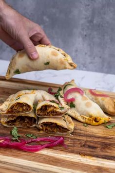 a person is cutting up some food on a wooden board with red onions and cilantro