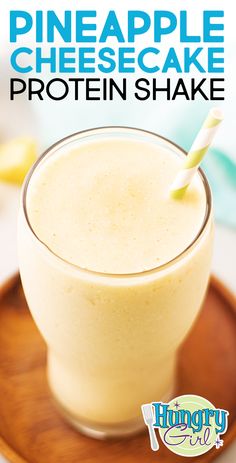 a pineapple cheesecake protein shake in a glass on a plate with a straw