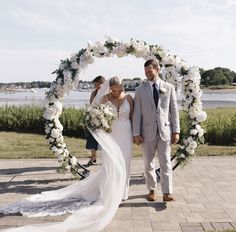 a bride and groom walking down the aisle at their outdoor wedding ceremony with white flowers