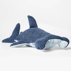 a stuffed shark toy laying on top of a white surface with its mouth open and it's eyes closed