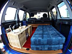 the interior of a van with blue couches and wicker baskets