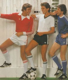 three men standing next to each other in front of a white wall with soccer balls