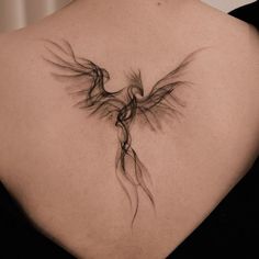 the back of a woman's shoulder with a bird tattoo on it