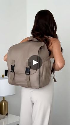 a woman with a backpack on her back is standing in front of a white wall