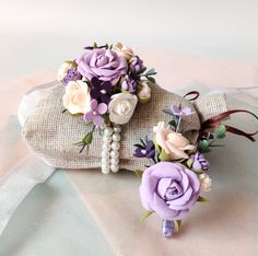 two purple and white flowers are placed on top of an old purse that is covered in burlap