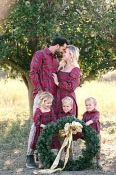 a man and two children are standing in front of a christmas wreath with their parents