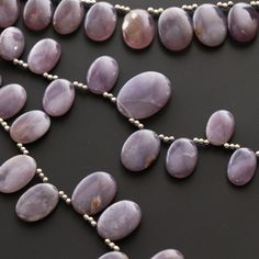 the necklace is made up of large purple beads and silver balls on a black surface