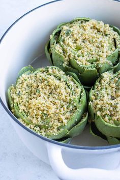 four stuffed green peppers in a white pot with parmesan cheese and seasoning