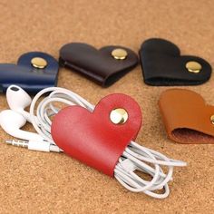 three heart - shaped leather cases with earbuds in them on a corked surface