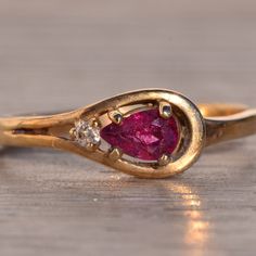 Uno Calle: Ruby And Natural Diamond Ring In Yellow Gold. The Ring Features A Pear Brilliant Cut Natural Ruby Set East To West With A Round Cut Natural Diamond At Its Point. The Gemstones Are Set Within A Sweeping Yellow Gold Loop That Continues Down Into The Shank. The Ring Is Crafted In Yellow Gold And Currently A Finger Size 5.57 Yet Can Be Adjusted To Any Finger Size For An Additional Charge On Request. Formal Teardrop Ruby Ring In Fine Jewelry Style, Formal Teardrop Ruby Ring Fine Jewelry, Teardrop Ruby Ring For Formal Occasions, Formal Ruby Teardrop Ring, Elegant Teardrop Ruby Ring For Formal Occasions, Yellow Gold Teardrop Ruby Ring For Anniversary, Ruby Set, Natural Diamond Ring, Natural Ruby