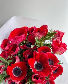 a bouquet of red flowers sitting on top of a white table cloth covered in paper